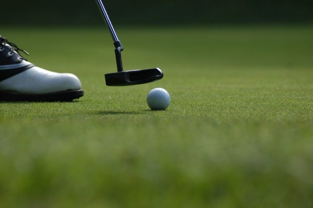 Golfer lining up a putt with a white ball on a green